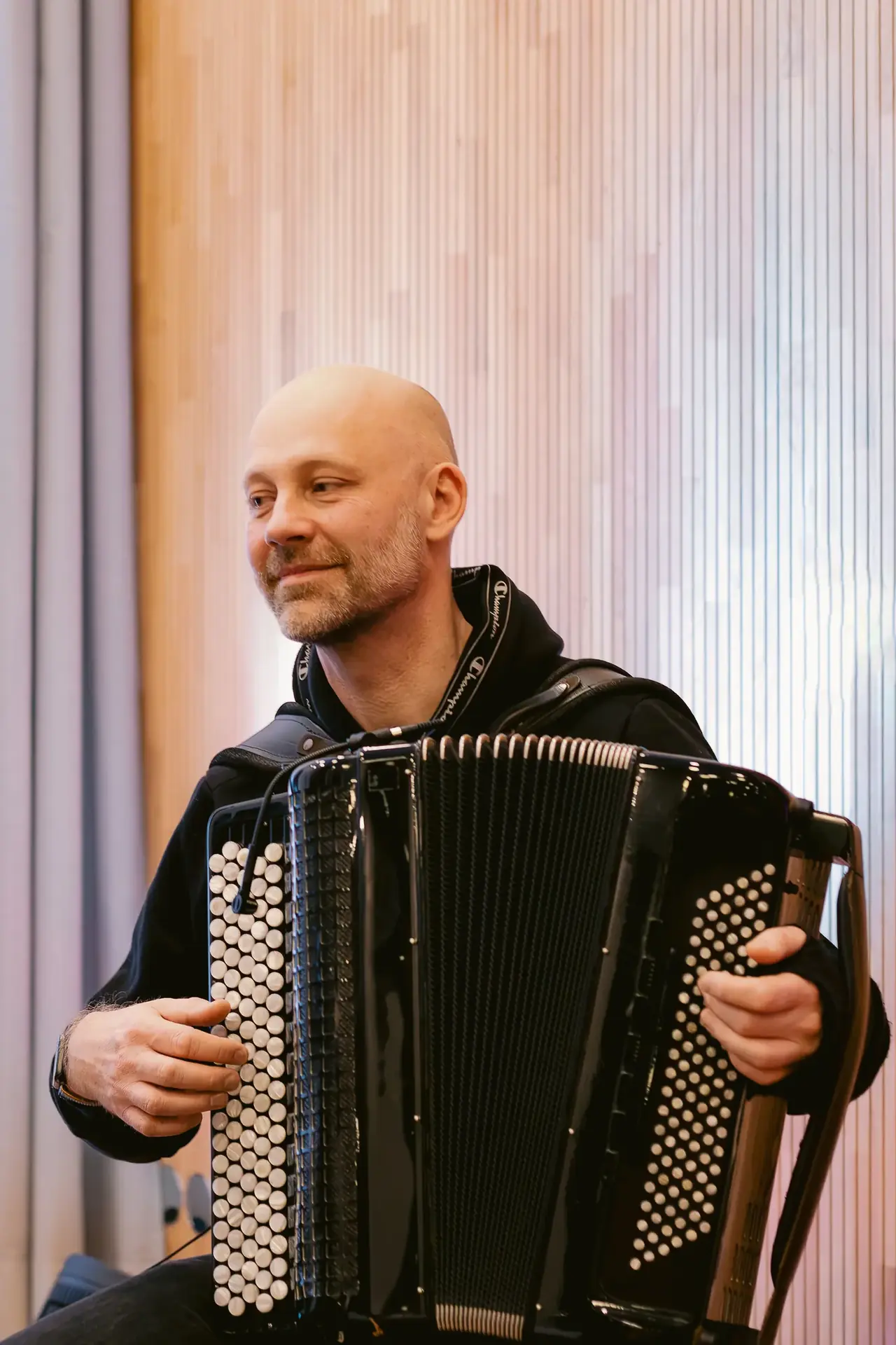 Harald Oeler mit Akkordeon vor Holzlamellenwand